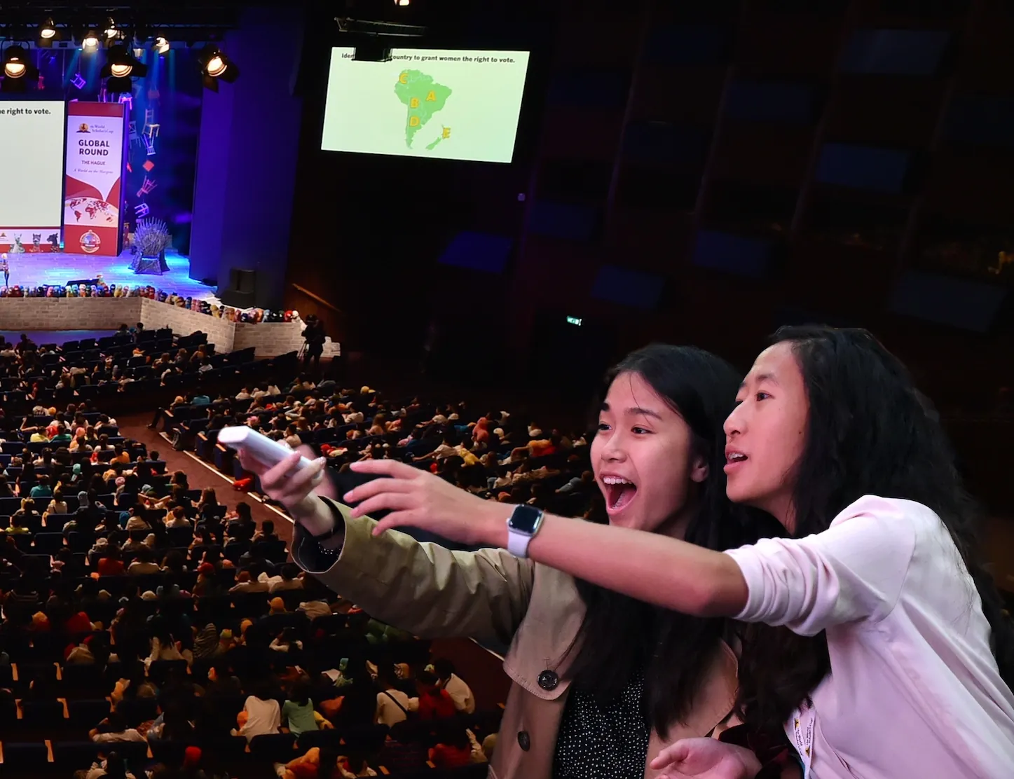 Two scholars point excitedly, clicker in hand, in a packed theater