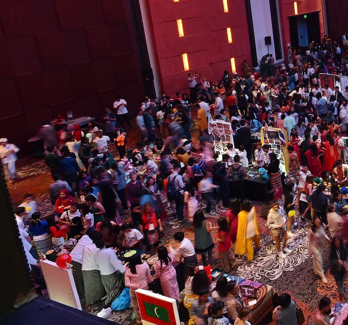 A crowded hall of booths and flags at the Scholar's Fair