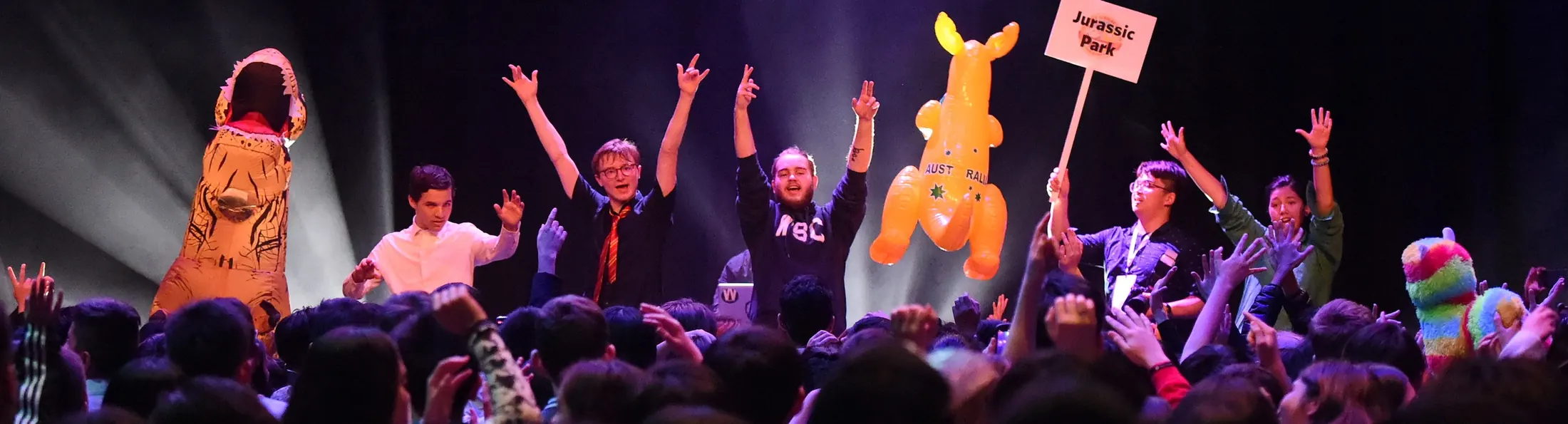 Scholars on stage with their arms raised, joined by an inflatable kangaroo