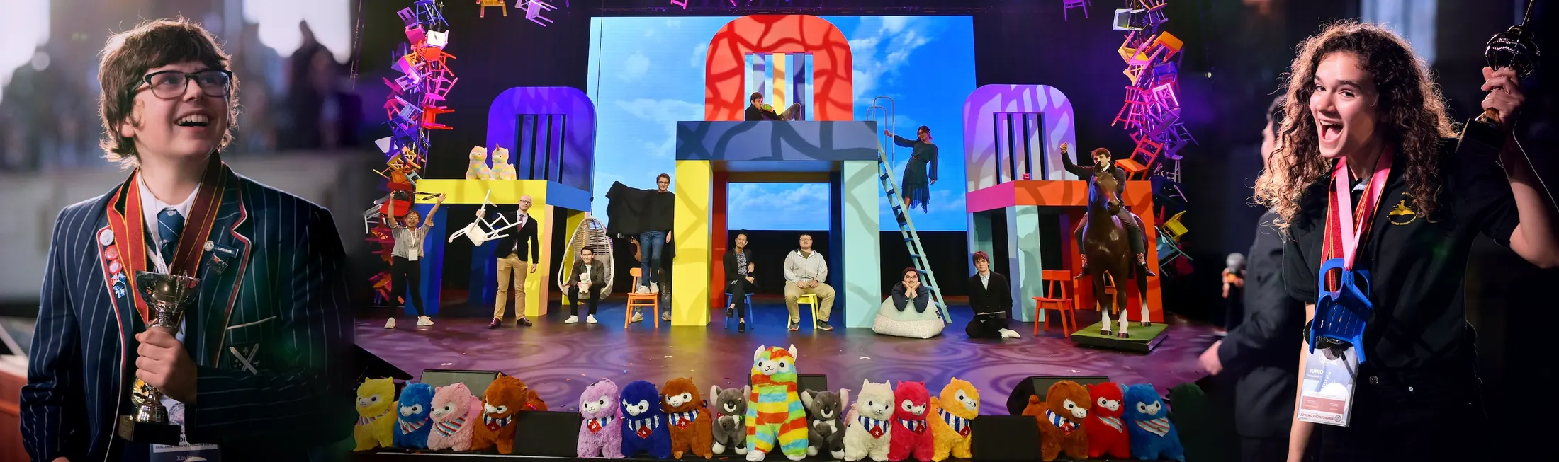 Scholars on stage in front of a colorful set and a row of toy alpacas