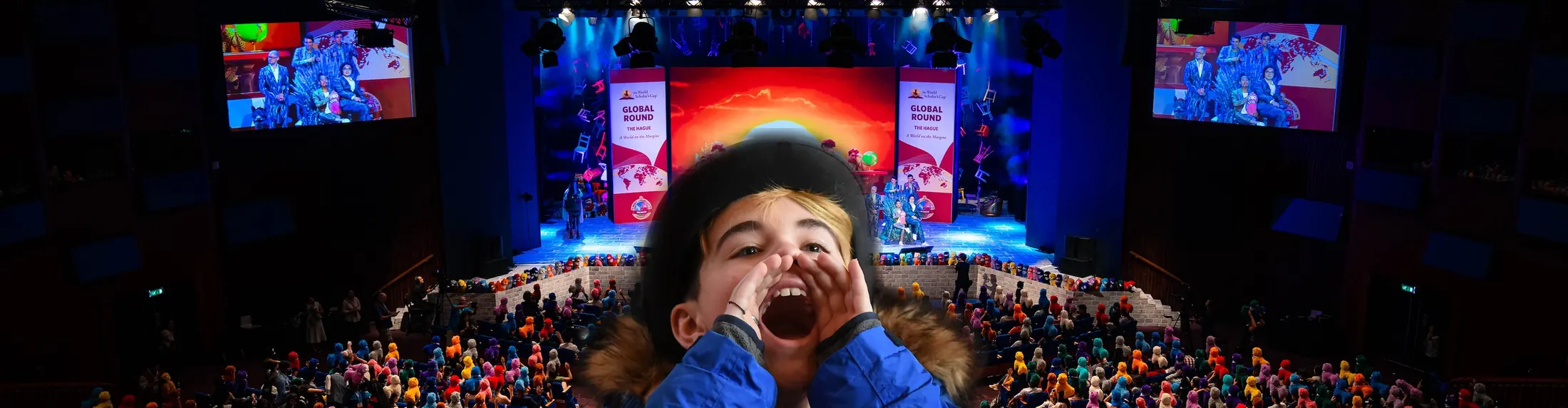 A scholar cheers in front of a packed theater at a Global Round